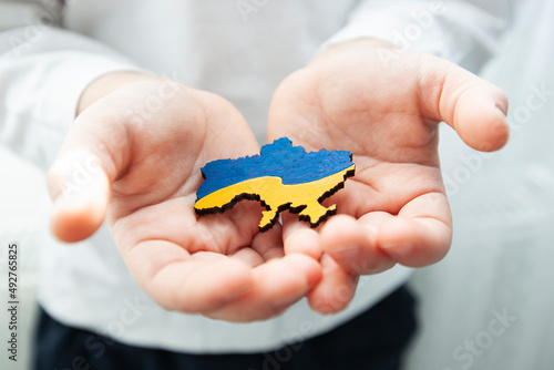 Boy holding wooden shape of Ukraine colored in national colors in hand
