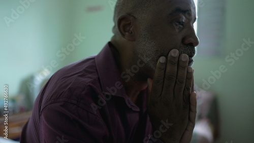 A depressed senior man sitting by bedside having emotional problems suffering alone