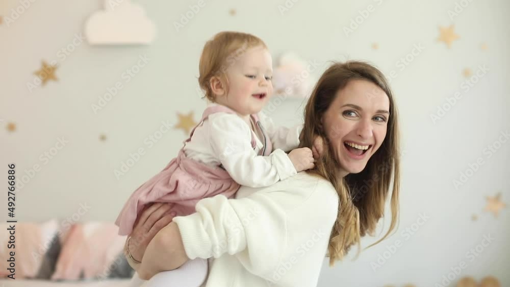 Happy mom rolls her little daughter on her neck. Family, values. Mom and daughter are having fun at home. Happy mom rolls her little daughter on her neck. Family, values. Mom and daughter are having fun at home.