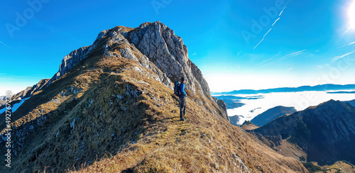 A man enjoying the panoramic view from mount Eisenerzer Reichenstein in Styria, Austria, Europe. The Ennstal valley is covered in clouds and fog.Hiking trail,Wanderlust. Sunny day.Freedom concept photo