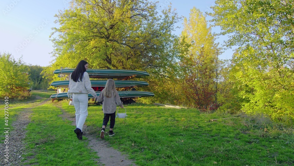 A happy family. Mom and daughter are walking in the forest park. Happy family concept. Mom and daughter are walking hand in hand in the forest park.