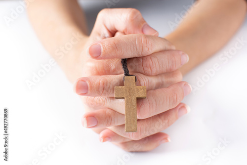 Woman praying with Rosary catholic cross on white background photo
