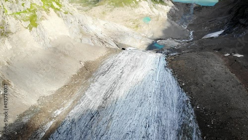 Aerial view with pan up from the crevasses of Stein glacier up towards heart shaped lake at Sustenpass, Switzerland with a view of tall peaks of the Swiss Alps photo