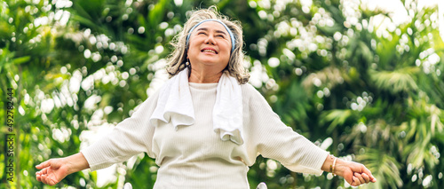 Portrait of happy senior old adult elderly asia women smiling standing and stretch her arms relax and enjoy with nature feeling breath fresh clean air in green park.Healthcare #492782444
