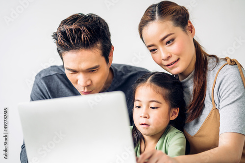 Portrait enjoy happy smiling love asian family father and mother with little asian girl learning and looking at laptop computer studying with online education e-learning system with teacher at home © Art_Photo