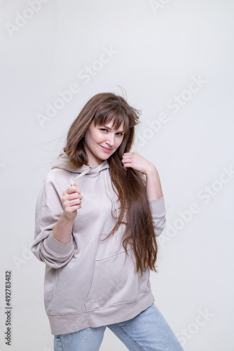 Wallpaper Mural portrait of a pretty blonde girl with long hair in a beige hoodie on a light background Torontodigital.ca