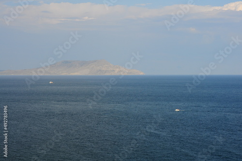 Seascape from a height to the sea and mountains in the distance, blue atmospheric haze. Black sea in summer with boats