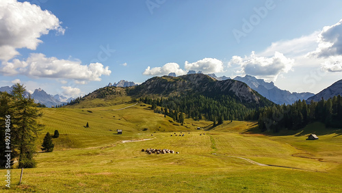 A panoramic view on the high Italian Dolomites from the top of Strudelkopf. There is a wide gravelled path leading to the top. Sunny day. A few clouds above the high peaks. Lush green plateau around © Chris