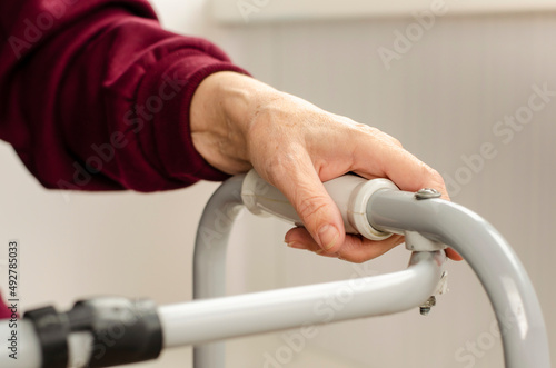 Hands of a senior woman on the handles of a walker. Rehabilitation and healthcare concept.