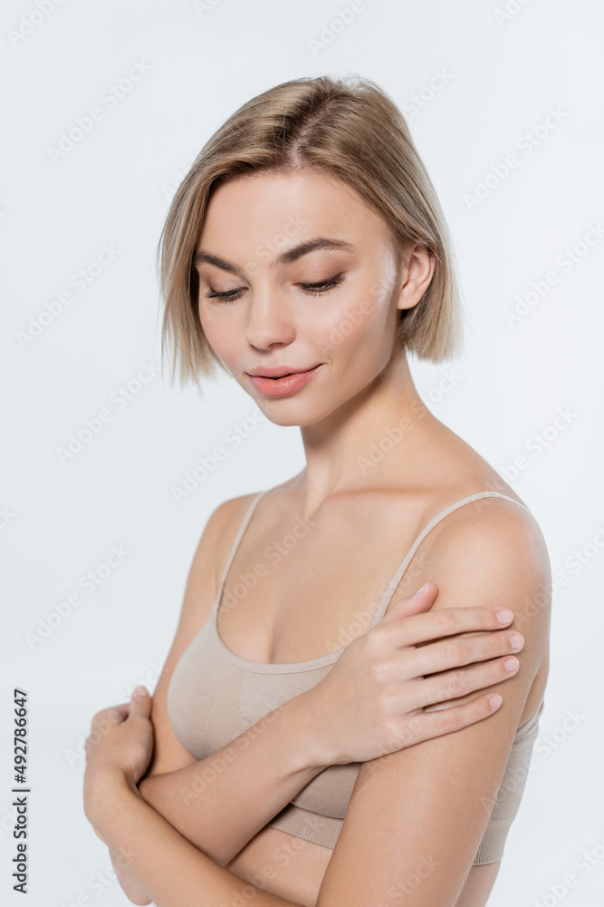 Young blonde woman touching shoulder isolated on grey. Young blonde woman touching shoulder isolated on grey.