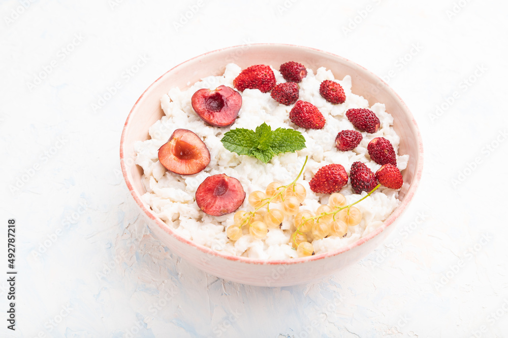 Rice flakes porridge with milk and strawberry in ceramic bowl on white concrete background. Top view. Rice flakes porridge with milk and strawberry in ceramic bowl on white concrete background. Top view.