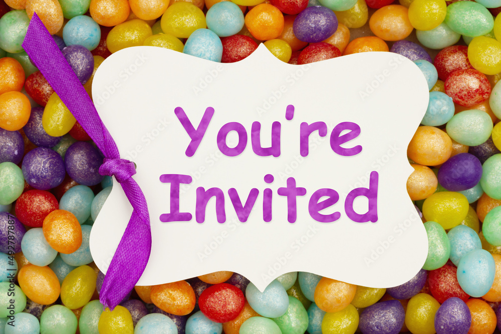 Youre invited message on a gift tag over colorful jellybean candy
