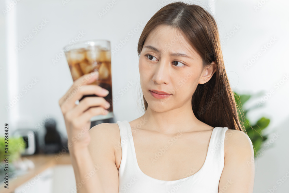 Avoid, limits sweet sugar, choose asian young woman, girl holding, looking at a glass of cold cola soft drink soda, sparkling water with ice by her hand. Health care, healthy diet lifestyle concept. Avoid, limits sweet sugar, choose asian young woman, girl holding, looking at a glass of cold cola soft drink soda, sparkling water with ice by her hand. Health care, healthy diet lifestyle concept.