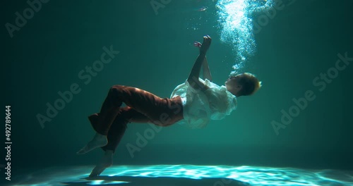 Incredible cinematic underwater view, young beautiful woman slowly sinks down helplessly slow motion. Depression concept photo