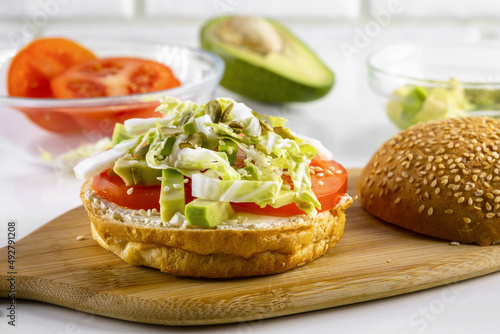 Vegetarian toast with cottage cheese, tomatoes, avocado, Chinese cabbage, pumpkin seeds and sesame seeds on a white table