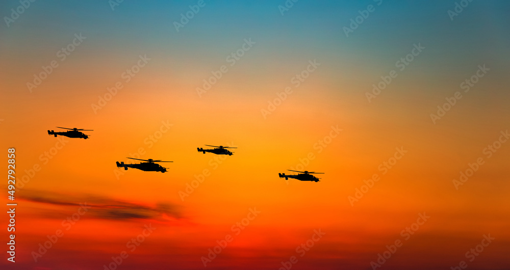 War helicopters silhouettes on sunset sky.