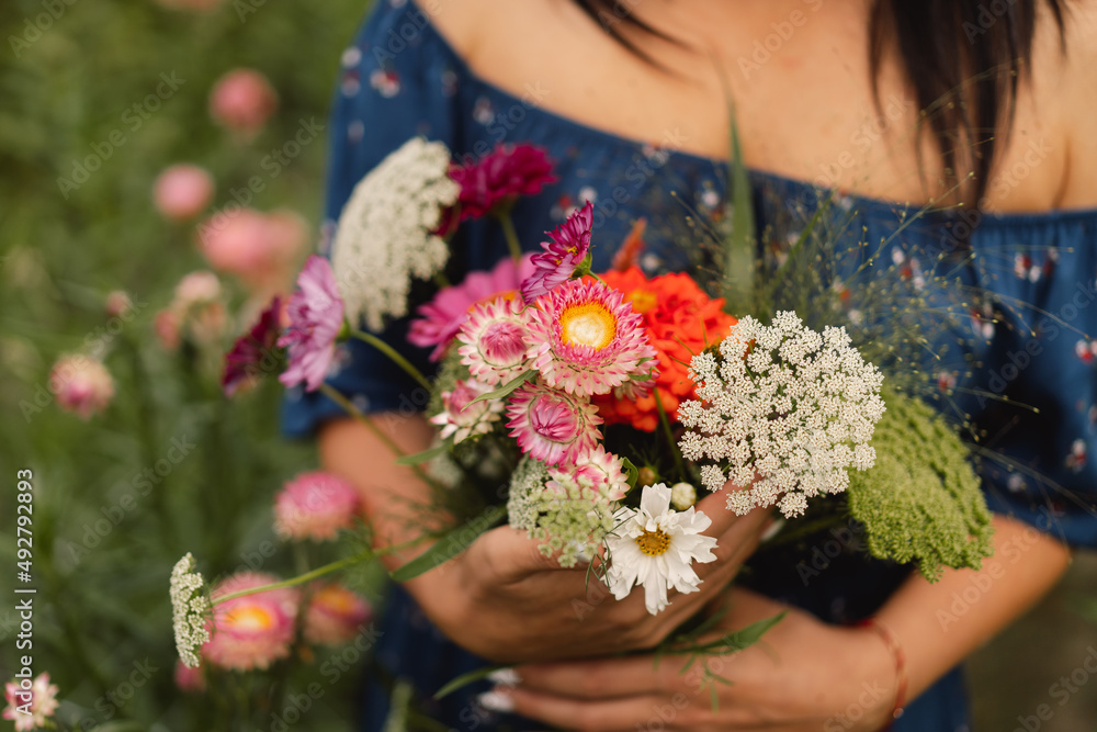 A Young woman walks with a bouquet of flowers in a floristic flower farm. Woman florist. Floristics concepts.