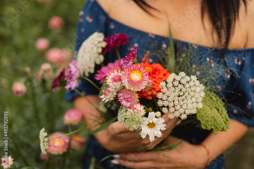A Young woman walks with a bouquet of flowers in a floristic flower farm. Woman florist. Floristics concepts.