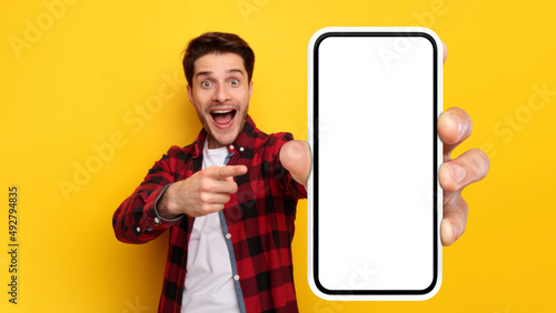 Shocked guy pointing at white empty smart phone screen photo