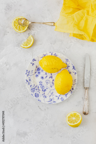 Vintage plate with lemons on white background yellow napkin and vintage knife and spoon