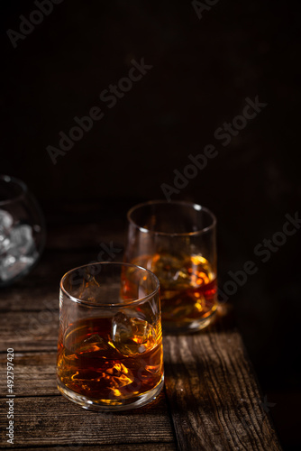Two glasses of the whiskey with ice isolated on a dark background