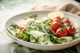 Green spring salad with arugula, cucumbers and tomatoes on tile background. Healthy vegetable vegan dish.