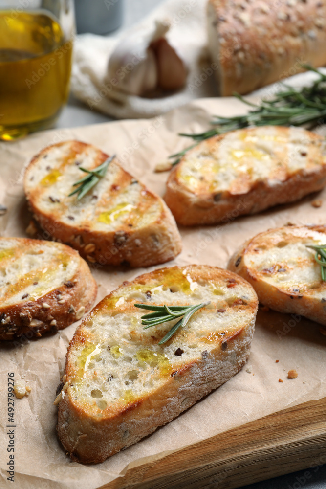 Tasty bruschettas with oil and rosemary on wooden board, closeup