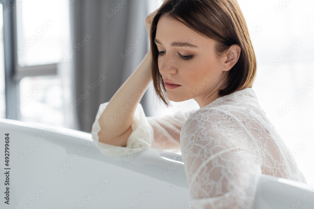 Woman in lace robe looking at robe at home