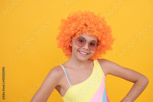 happy teen girl portrait in sunglasses and swimsuit wearing orange curly wig hair, happiness.