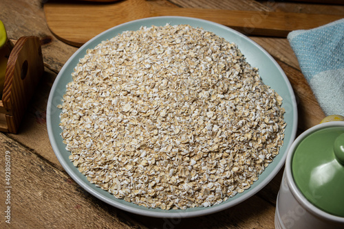 Dry oatmeal in a plate on a wooden background. Healthy and tasty food. Food for weight loss