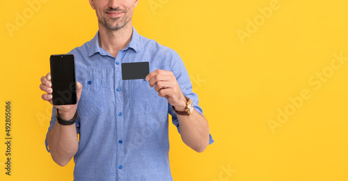 Принти на полотні cropped man showing smartphone and business card with copy space, online banking