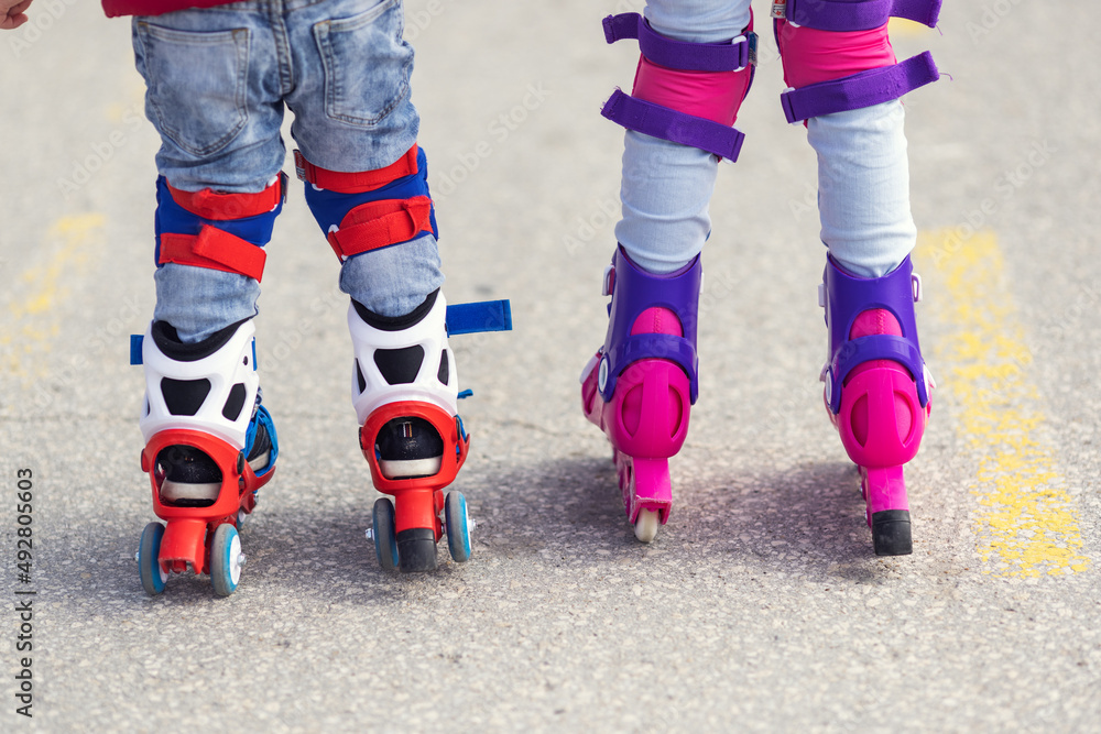 Obraz premium Kids boy and girl having fun outdoor while riding roller skates. Children on rollerblades. Roller skating in the park near seashore.