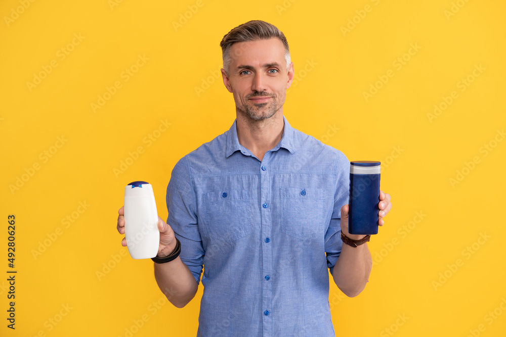 presenting cosmetic product for men. man use shower gel. guy choose shampoo bottle presenting cosmetic product for men. man use shower gel. guy choose shampoo bottle