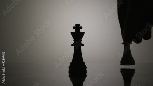 Feminism overthrowing the patriarchy concept, queen checkmating the king, chess pieces backlit  photo