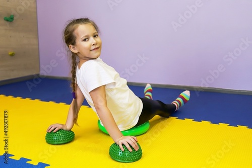 a little girl works on herself and stands in a rack on spiked balls and does push-ups in a children's center