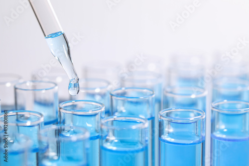 Dripping reagent into test tube on light background, closeup and space for text. Laboratory analysis