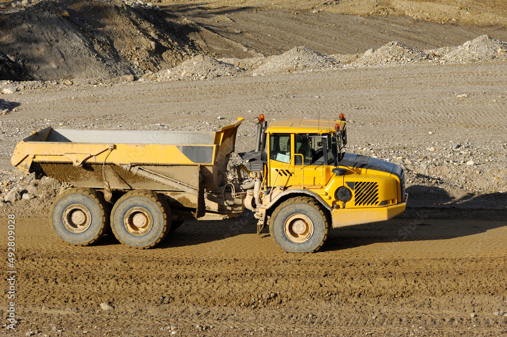 Yellow dump truck working in gravel pit