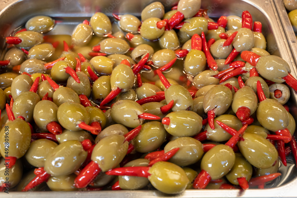 Green fresh olives with chili pepper close up on market, food background Green fresh olives with chili pepper close up on market, food background