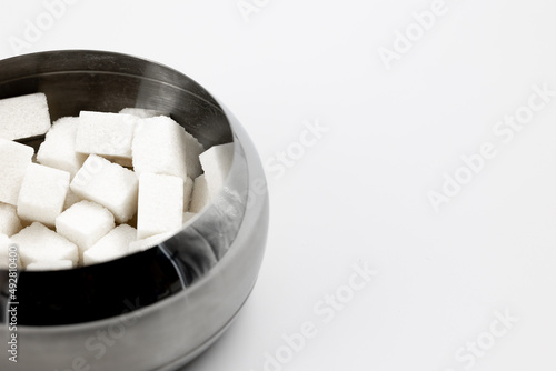 Metal bowl with cubes of white refined sugar for tea and coffee close-up