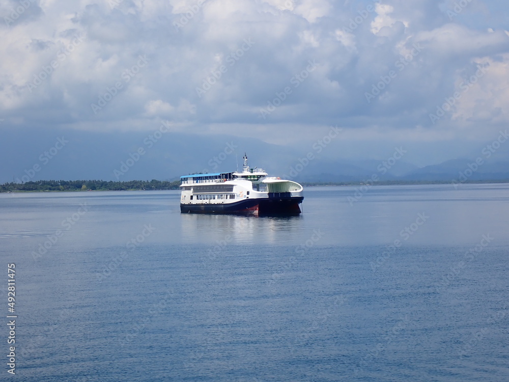 Passenger-and-freight ferry in a calm blue sea without waves.