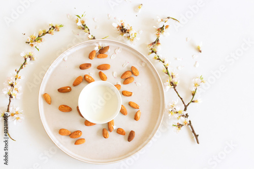 Flowering branch of almond and cup of almond milk on a white background.Healthy eating concept.Copy space.