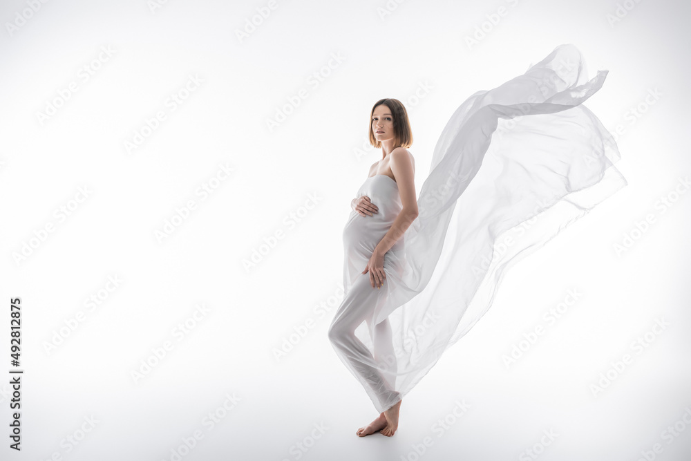 Full length of brunette pregnant woman posing with cloth on grey background Full length of brunette pregnant woman posing with cloth on grey background