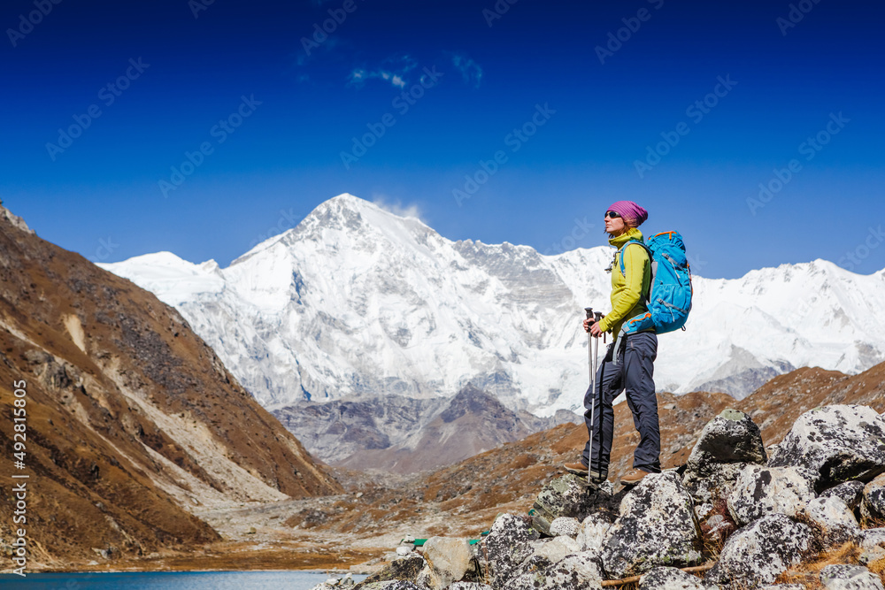 Woman Traveler with Backpack hiking in Mountains with beautiful summer Himalayas landscape on background. Everest Base Camp trek. Cho oyu mountain on the background