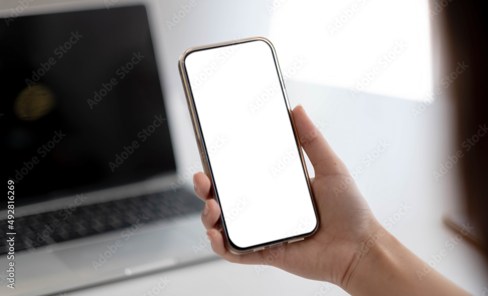 Cropped shot view of woman hands holding smart phone with blank copy space screen for your text message or information content, female reading text message on cell telephone during in office.