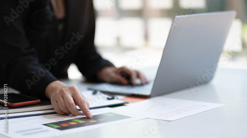 Close up Businesswoman hand holding pen and pointing at financial paperwork.