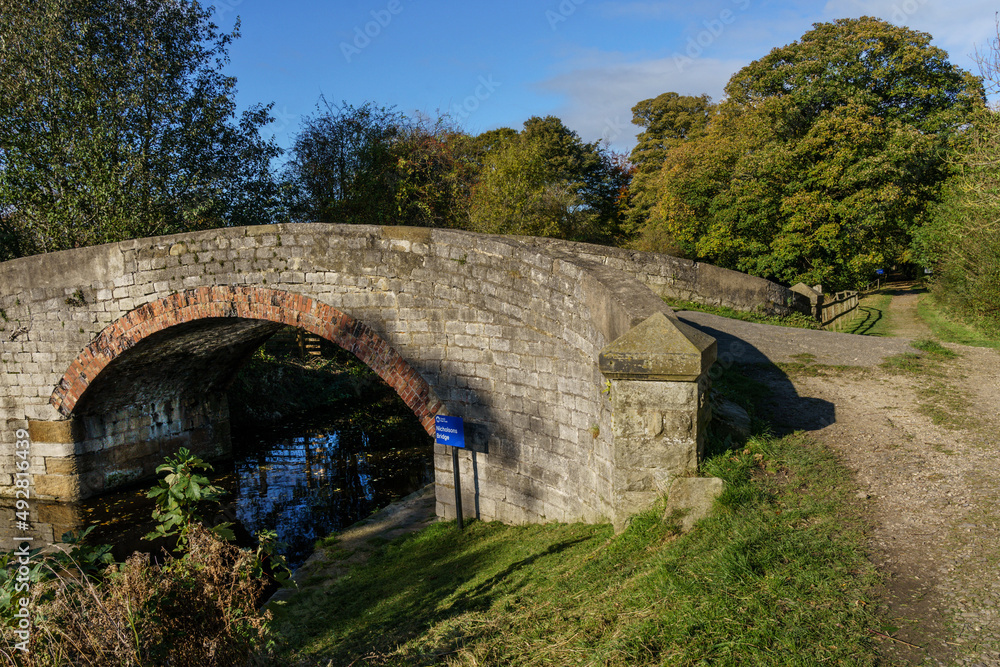 Stone arch bridge on a sunny day along The Ripon Canal, the bridge was built for farm vehicles and pedestrians and is still used today, Littlethorpe, Ripon, North Yorkshire, England, UK. 