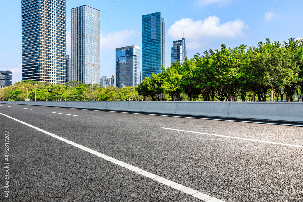 Asphalt road and city skyline with modern commercial buildings in Shenzhen, China.