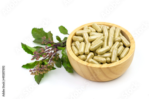 Capsule of Holy basil on wooden bowl isolated on white background. Holy basil leaf are useful herbs. 