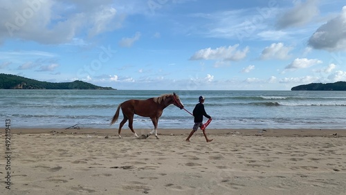 man walking with his horse on the beach