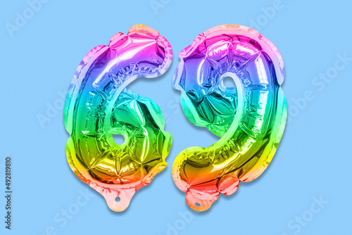 Rainbow foil balloon number, digit sixty nine on a blue background. Birthday greeting card with inscription 69. Top view. Numerical digit. Celebration event, template. photo